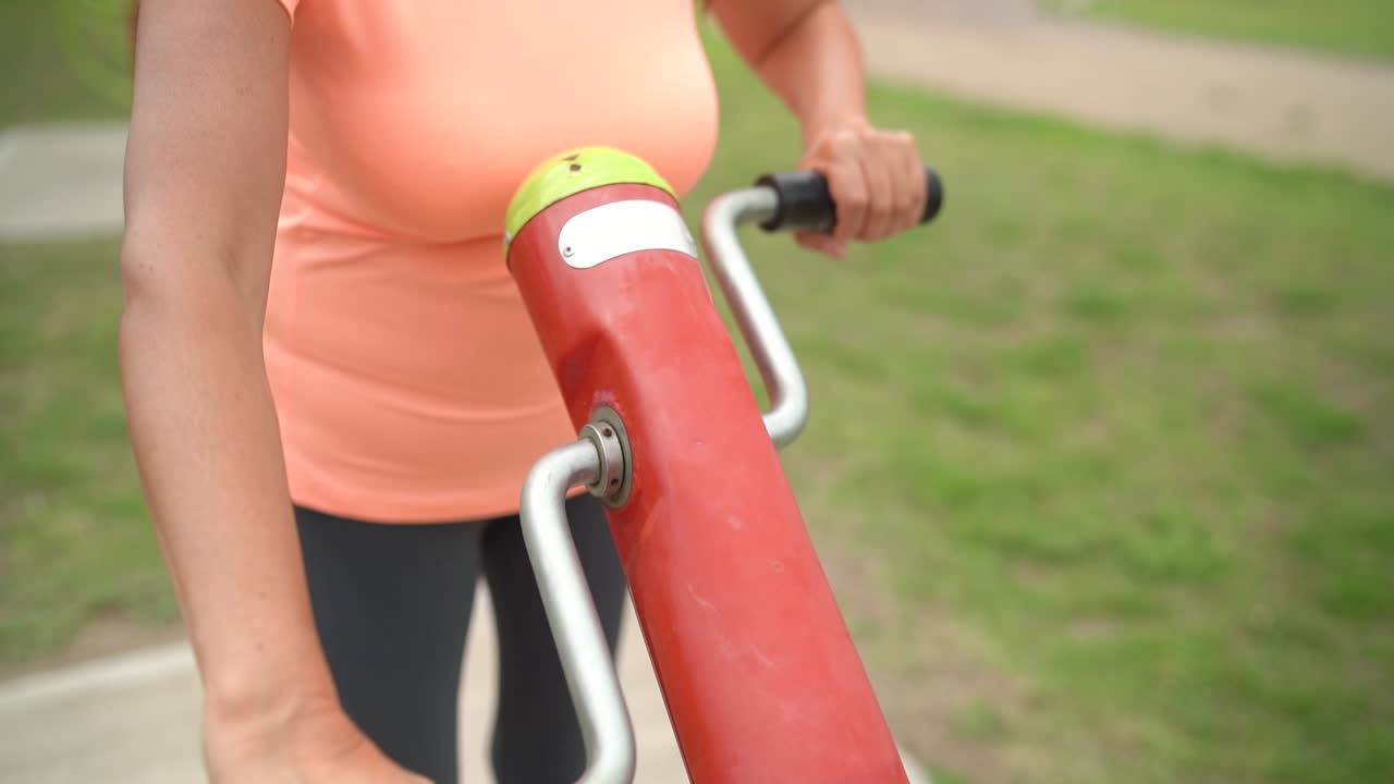 Al parco, una donna si allena con un pedale a mano - Rallentatore