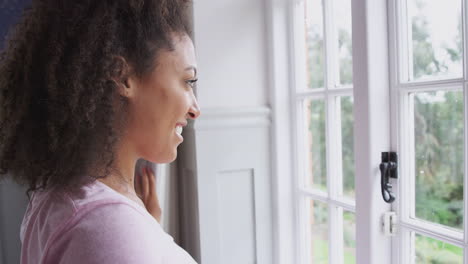 Woman-Wearing-Pajamas-Opening-Bedroom-Curtains-At-Start-Of-New-Day