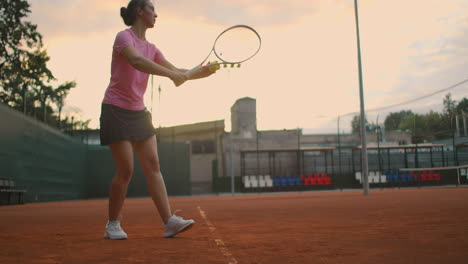 slow motion: young caucasian teenager female tennis player serving during a game or practice. tennis player serving on the clay court.