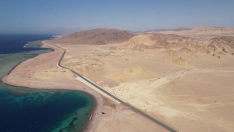 Inclinación-Aérea-Hacia-Abajo-Sobre-Los-Coches-En-La-Arena-De-La-Playa-En-El-Mar-Rojo,-Tabuk,-Arabia-Saudita