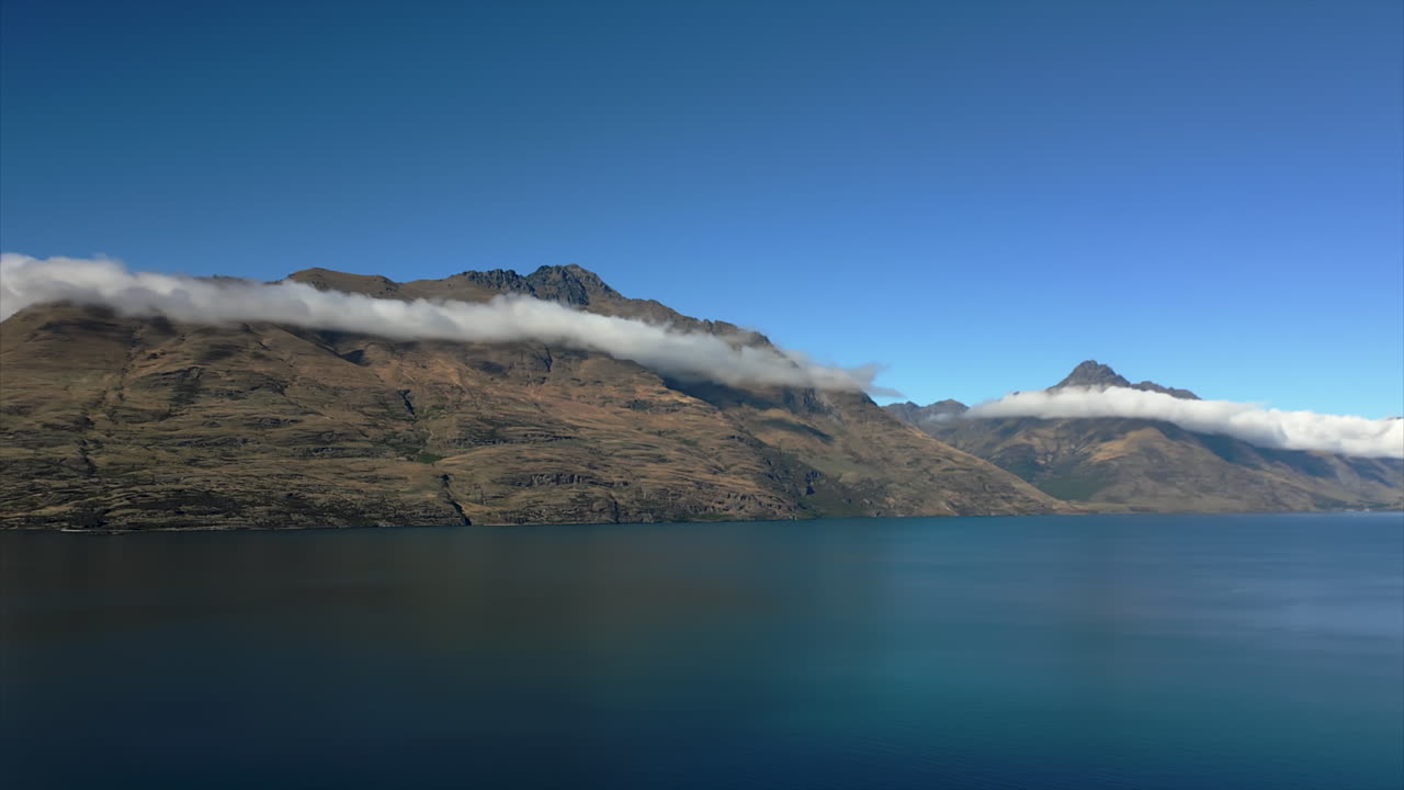 Montagne sopra il Lago Wakatipu con nuvole sotto le cime - panorama vicino a Queenstown, Nuova Zelanda.