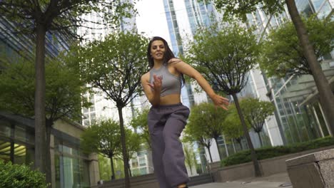 bailarina callejera de hip hop urbano con joggers, sujetador deportivo y entrenadores, mueve su cuerpo como una mezcla profesional de varios estilos de estilo libre al aire libre en la calle de la ciudad