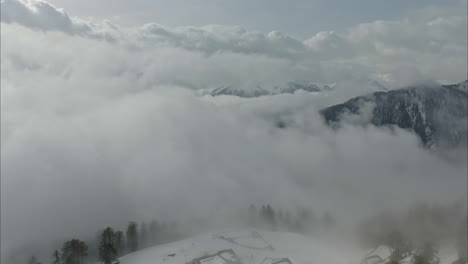 una vista aérea de un paisaje nevado cubierto de niebla en un clima nublado en austria