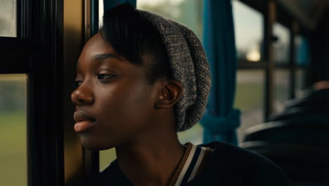 young woman looking thoughtfully out a window on public transport