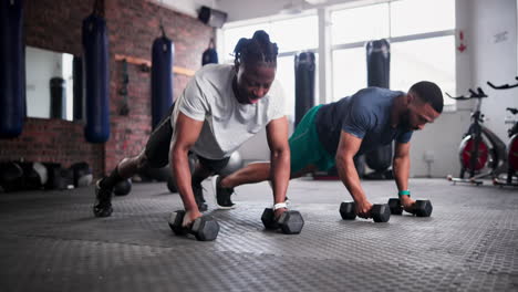 men doing push-ups with dumbbells in a gym