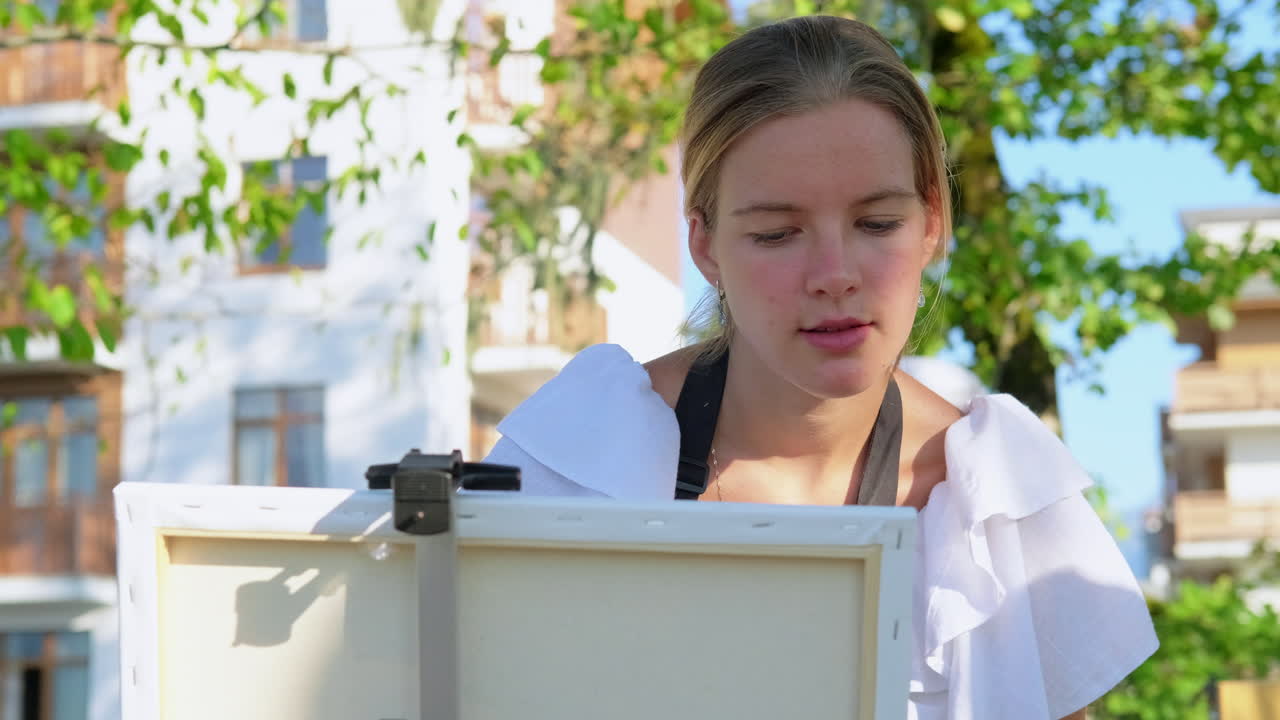 젊은 여성이 야외에서 그림을 그리고 있습니다.