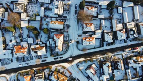 top down aerial of a car driving slowly over a frozen route in a suburban neighborhood on a sunny winter day