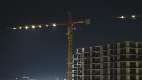 construcción por la noche. lapso de tiempo. grúa torre en un sitio de construcción con iluminación