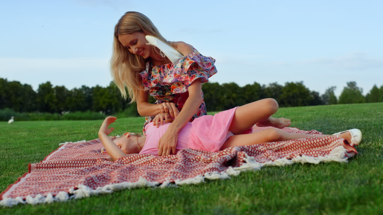 도시 공원에서 딸과 장난치는 여자, 풀 ⁇ 에서 일몰을 즐기는 가족