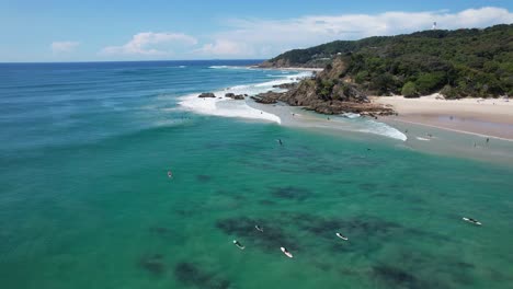 aerial view of surfers floating in the ocean in clarkes beach, nsw, australia - drone shot