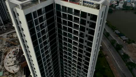 la grúa aérea descendente derribó un gran desarrollo de viviendas residenciales de gran altura del sudeste asiático con la expansión urbana en el fondo