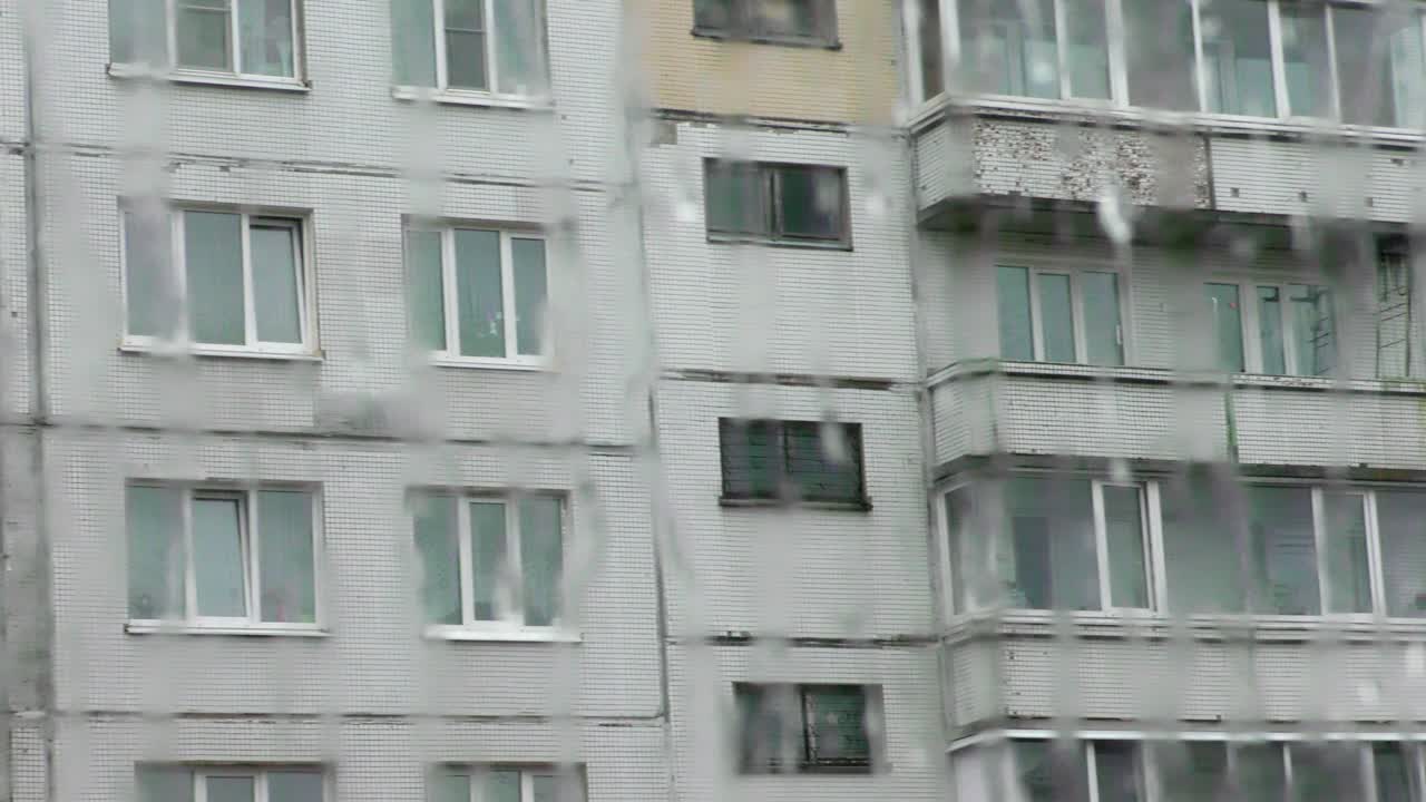 vista a través de una ventana lluviosa de un edificio de apartamentos.