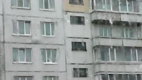 view through a rainy window of an apartment building.