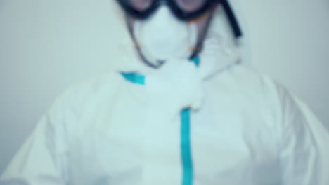 exhausted healthcare worker in protective suit breathing heavily after long hours of duty - out of focus shot