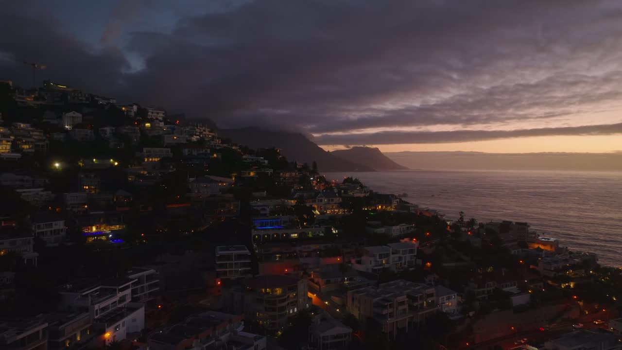 Breath taking elevated footage of residential borough at dusk. Luxurious residences in slope falling to sea coast. Cape Town, South Africa
