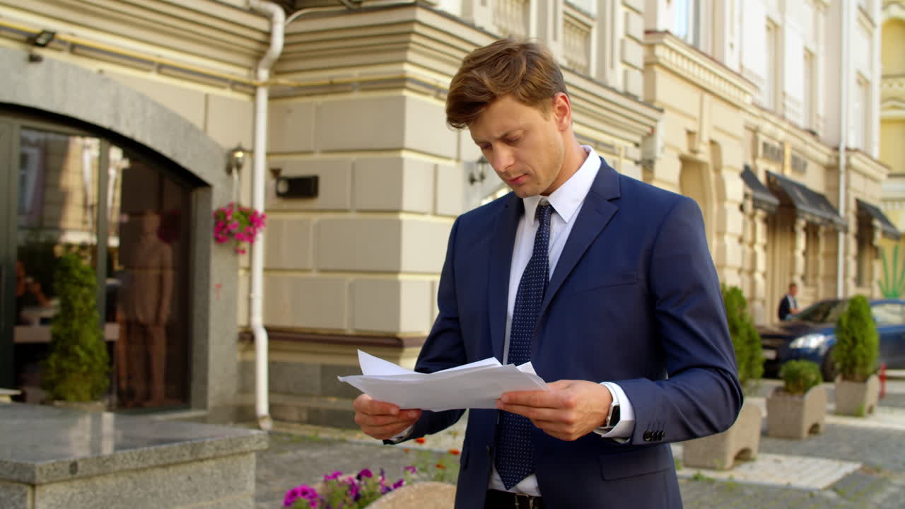 hombre de negocios enfocado leyendo documentos al aire libre. pensando profesional