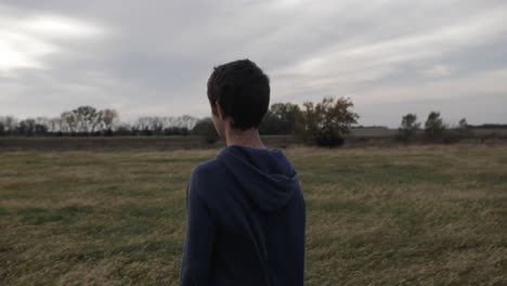 A-teenage-boy-stands-in-a-Kansas-wheat-field-at-sunset