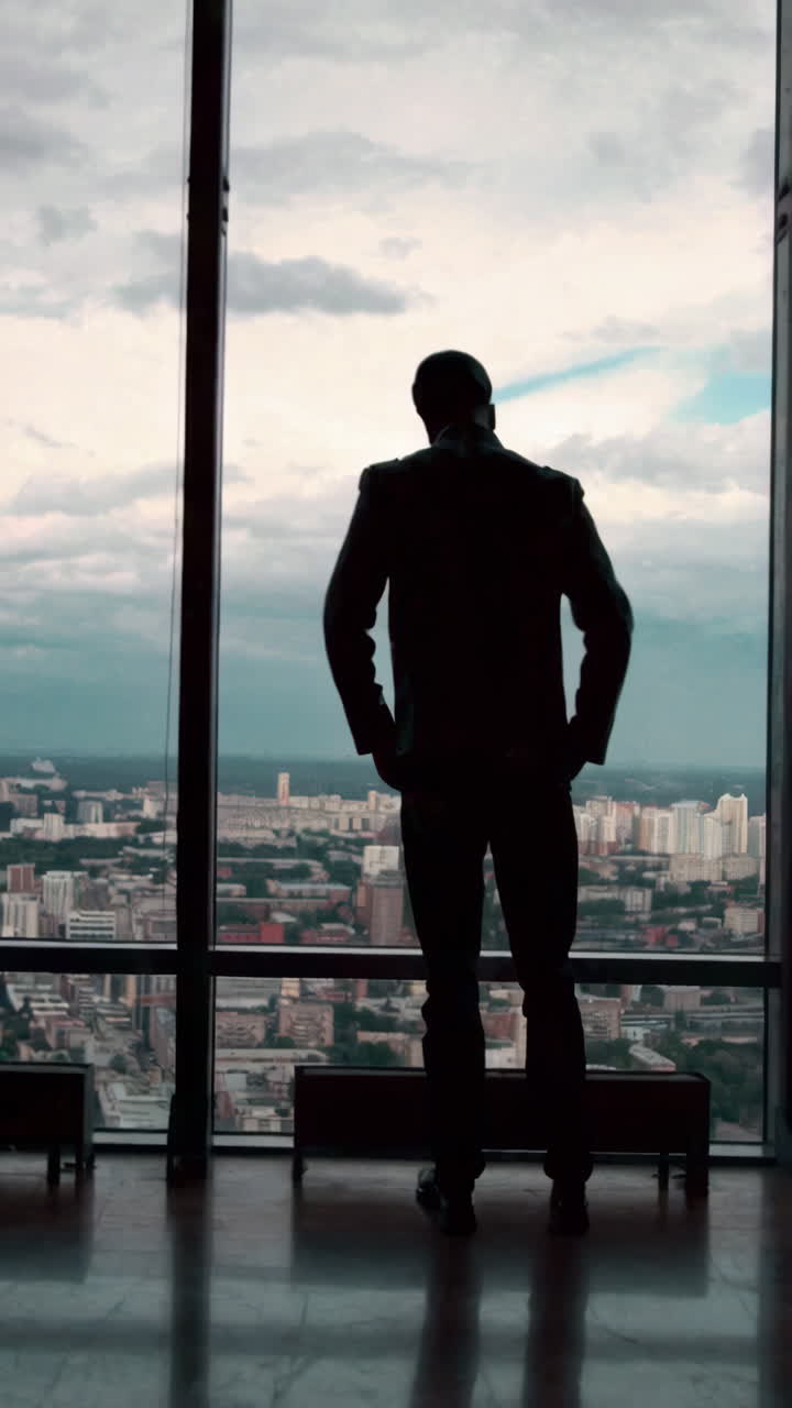 Businessman Looking Out at Cityscape from High-Rise Window