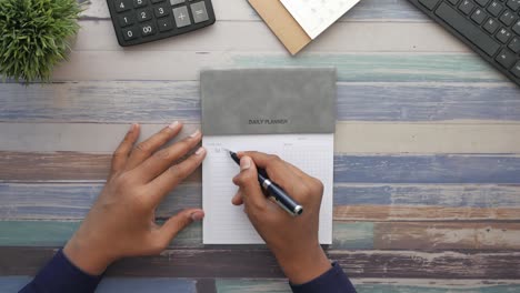 Top-view-of-men-writing-weekly-planner-on-table