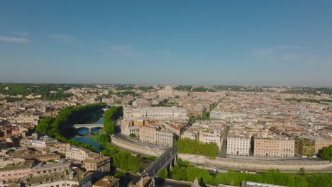 Aerial-cinematic-footage-of-old-buildings-in-city.-Green-trees-along-Tiber-river-bending-around-centre.-Rome,-Italy