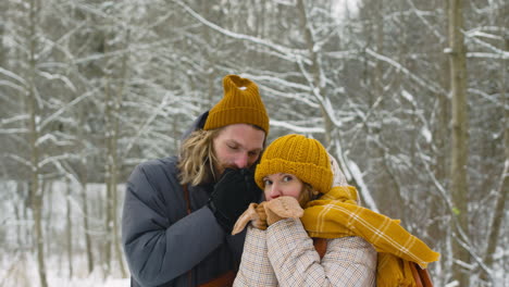 Hombre-Y-Mujer-Calentándose-Las-Manos-En-El-Bosque-Nevado-1