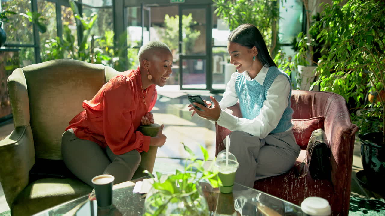 Two women using a phone in a cafe