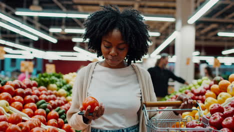 woman shopping for fresh produce in a supermarket while using her mobile phone
