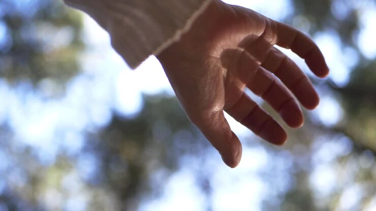 Eén hand reikt uit tegen een bokeh-achtergrond, medium shot