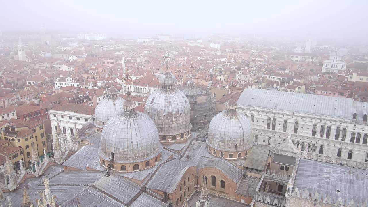 Fog sets in over round towers of saint mark's basilica, venice italy aerial