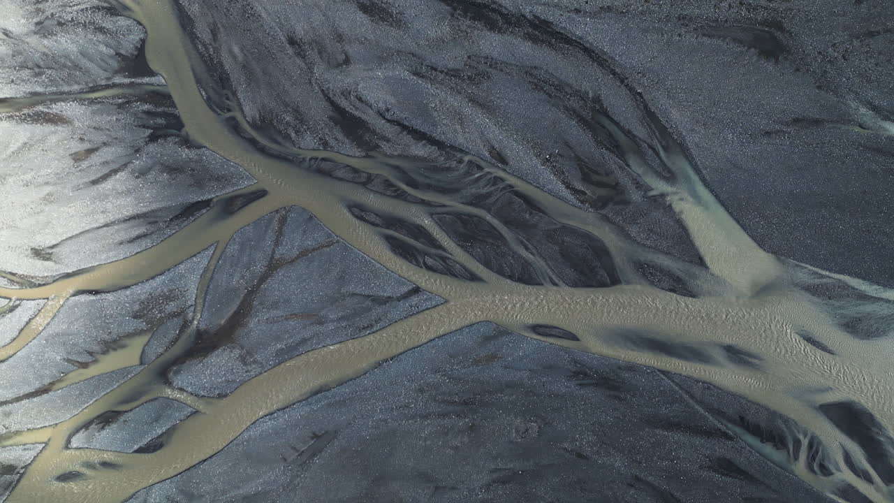 Top-down aerial view of intertwining glacial rivers forming abstract natural patterns, Iceland