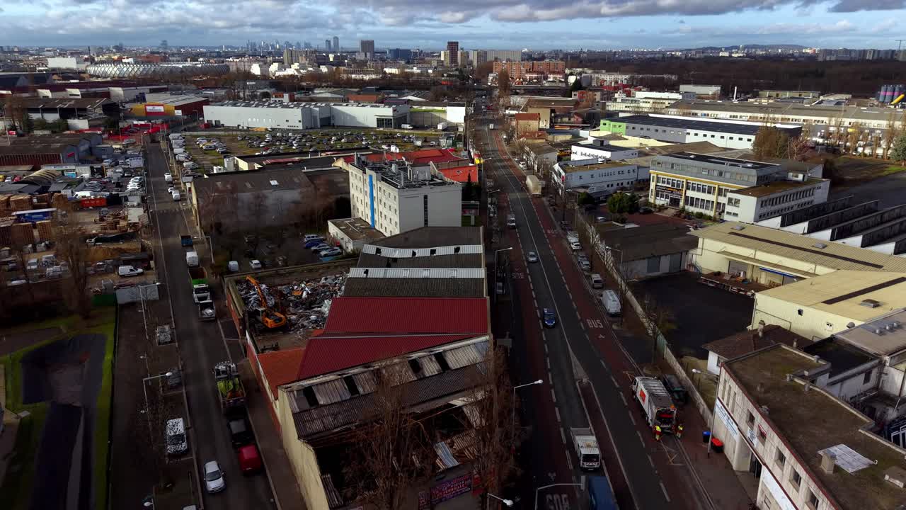 Gata i kommersiellt och industriellt område med La Défenses silhuett i fjärran i en Parisförort, Frankrike. Flygbild framåt.