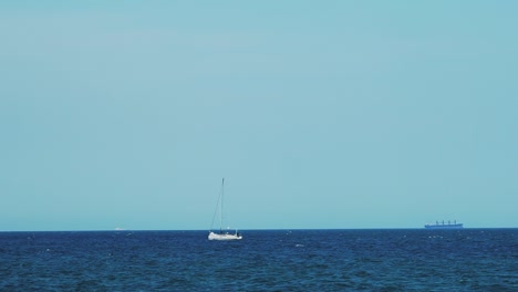 the yacht is under sail floats in the sea. on the horizon are seen cargo ships