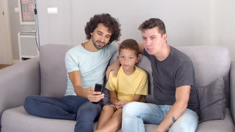 Dos-Padres-Concentrados-Y-Su-Hijo-Estudiando-El-Control-Remoto-De-Un-Televisor-Nuevo