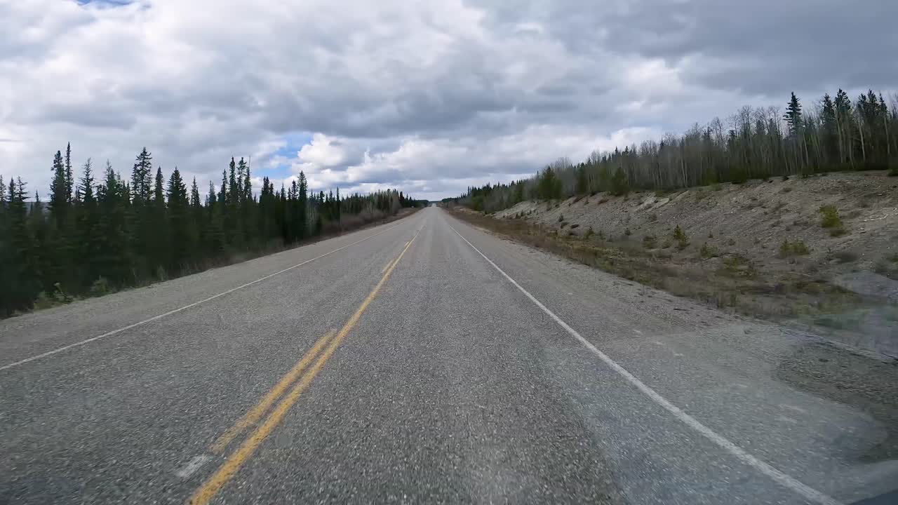 POV - driving on the international Alaska Highway through a taiga forest in in the White River Valley in Yukon on in the early spring; concepts Alaska Highway, travel, wilderness and adventure