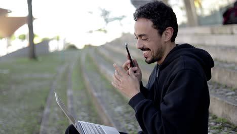 hombre feliz usando portátil y teléfono inteligente