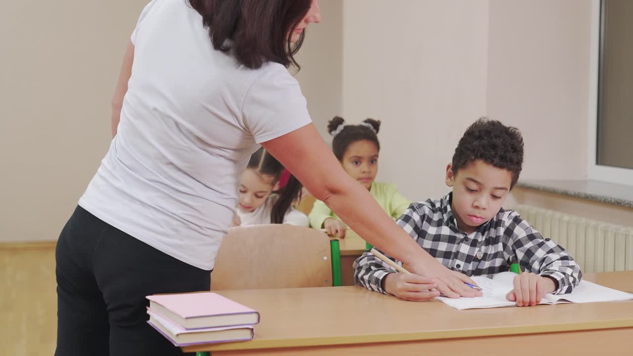 el maestro chequeando el cuaderno del alumno en el aula.