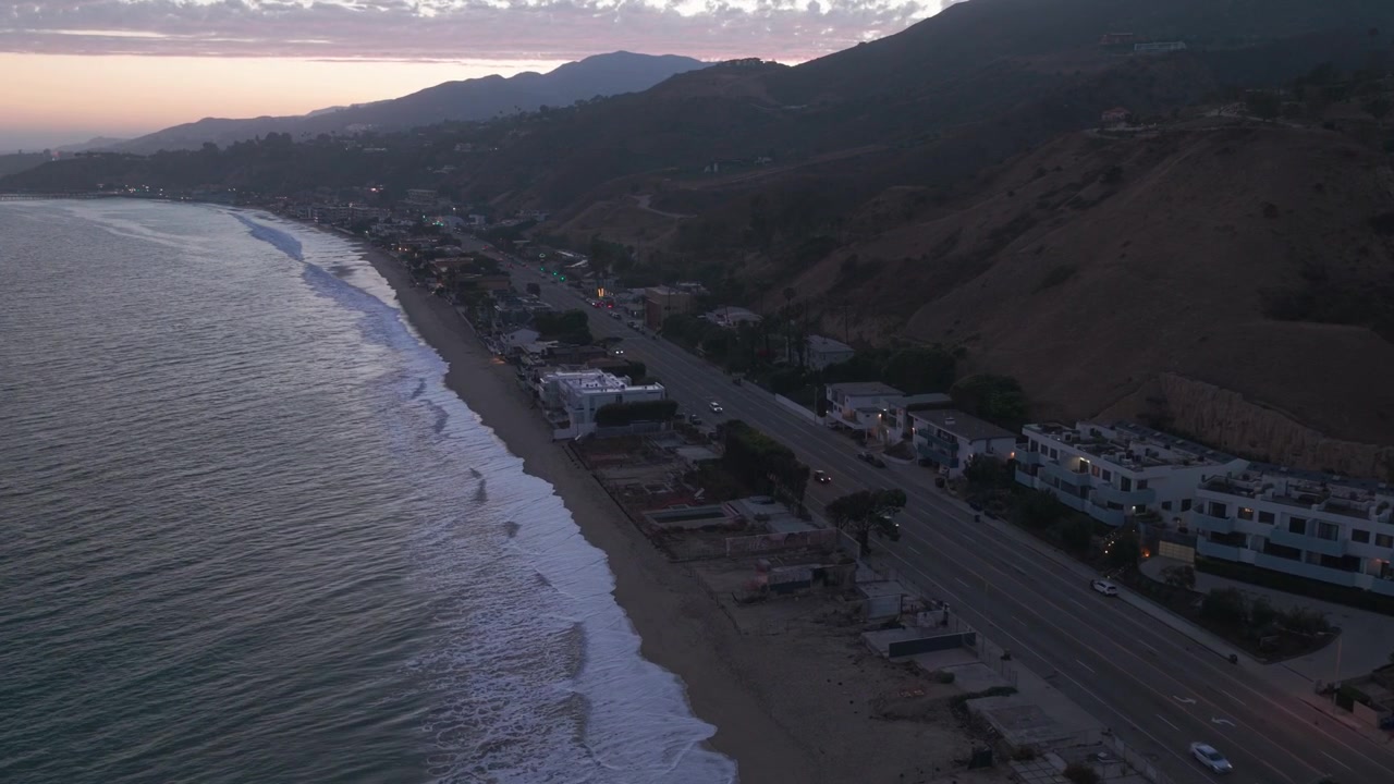 Ripresa aerea bassa con carrello delle rovine delle fondamenta lungo la Pacific Coast Highway dopo l'incendio a Malibu, California, durante il tramonto. 4K