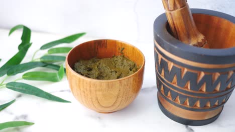 henna paste in wooden bowl with mortar and pestle