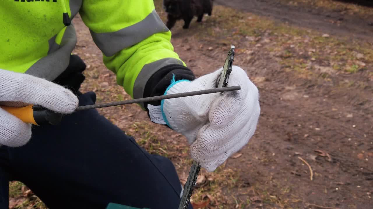 Person in green safety jacket sharpen chainsaw chain with round file