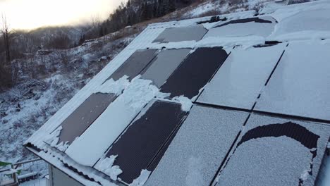 Snow-covered-solar-panels-closeup---Low-production-during-winter-season---Dusk-morning-light-backward-moving-aerial---Norway
