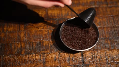 hand scooping coffee grounds into a ramekin