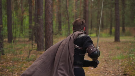 Strong-knight-holds-sword-running-through-forest-backside