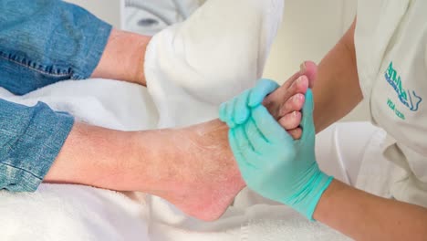 esteticista está masajeando suavemente los pies del hombre con una crema en un estudio de masajes