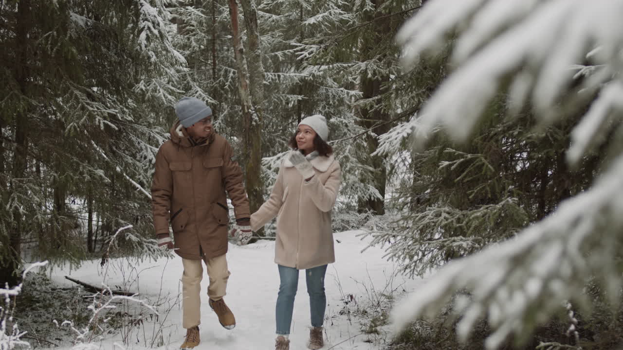 una pareja caminando de la mano en un bosque nevado
