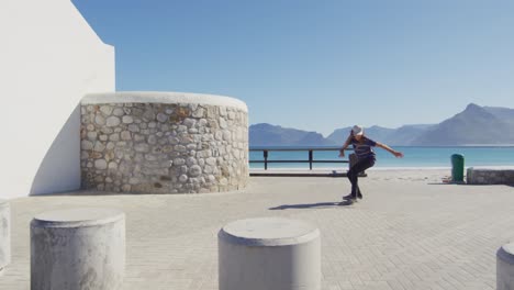 video of caucasian man with dreadlocks skateboarding on sunny beachside promenade