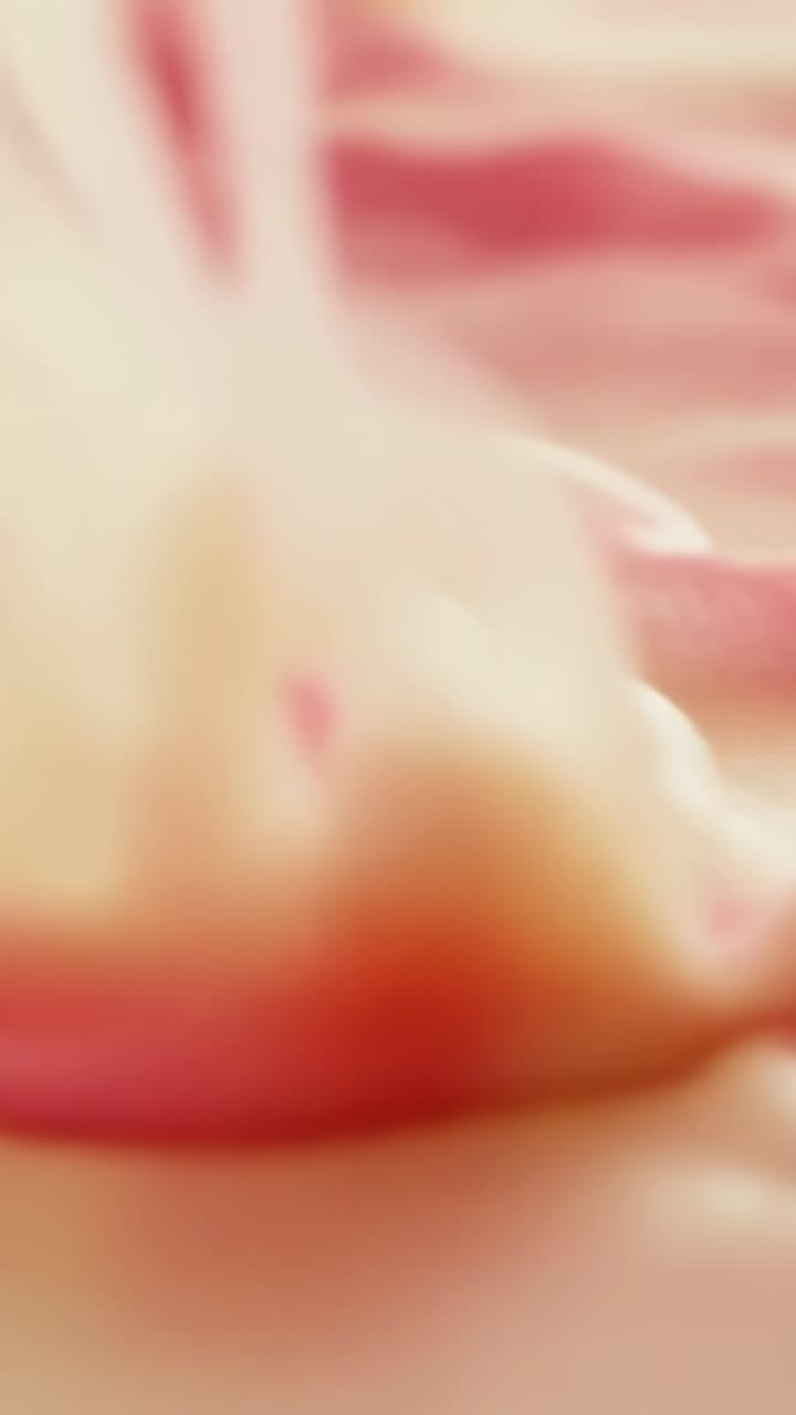Video verticale: cumulo in movimento che causa la levigatura dello strato di crema in macro, formando chiazze, grumi dorati e striature