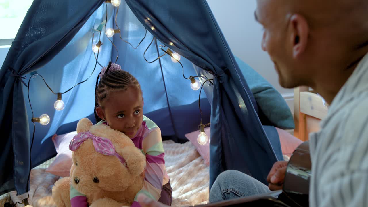 African American father and girl, father approaching tent, playing guitar, calming child with teddy