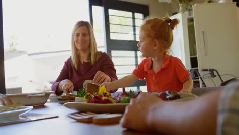 madre e hijo cortando un pan en la mesa de comedor 4k