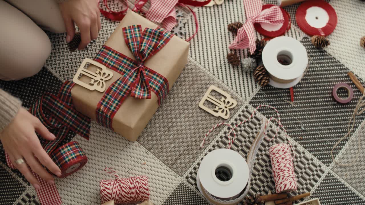 vista superior de una mujer caucásica irreconocible envolviendo regalos de navidad en el suelo.