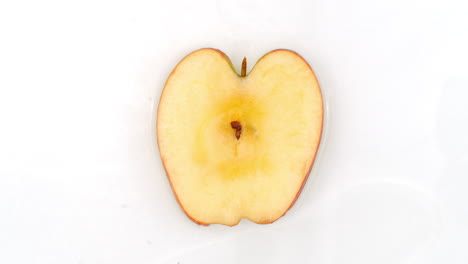 One apple lie on white in the background in slow motion falling water splashes.